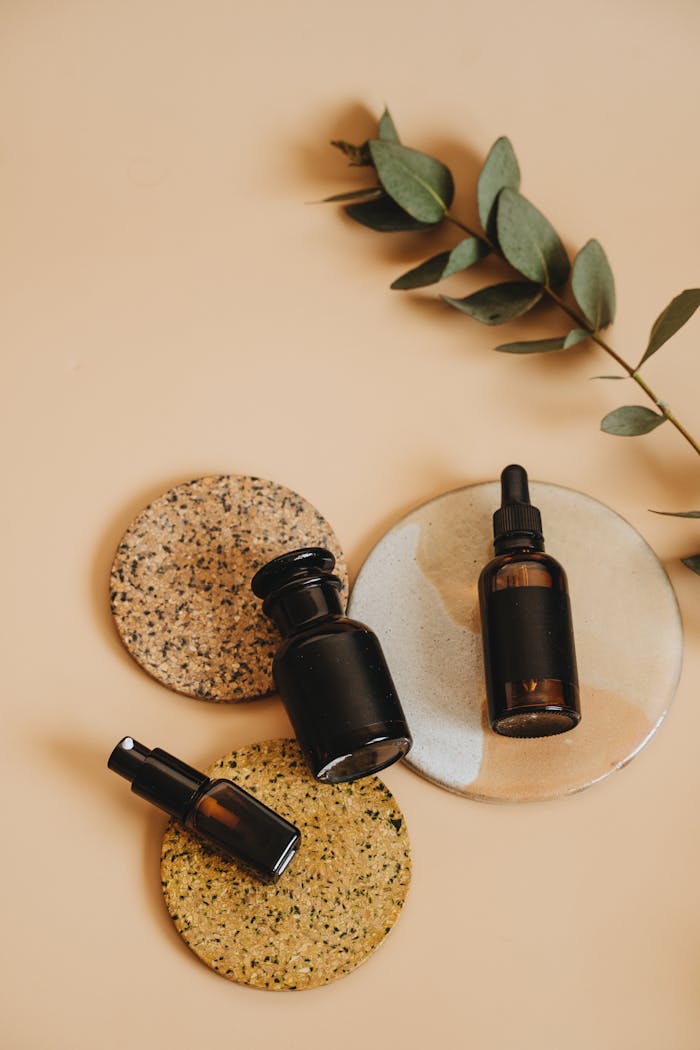 Elegant flat lay of cosmetic bottles on textured surfaces with eucalyptus leaves, ideal for skincare themes.