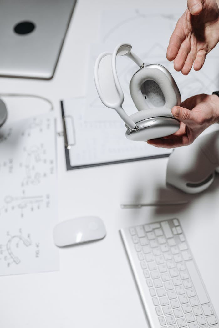 A clean workspace featuring wireless headphones, keyboard, and tech devices on a desk.
