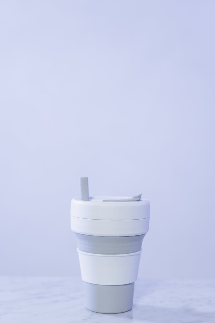A sleek, collapsible reusable cup with lid on a light background.